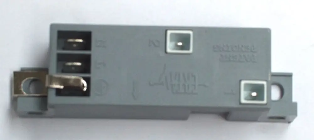 Graues Gehäuse mit Anschlüssen und einer metallischen Sicherung. Produkt von Daikin, wahrscheinlich Bestandteil eines Zündsystems.